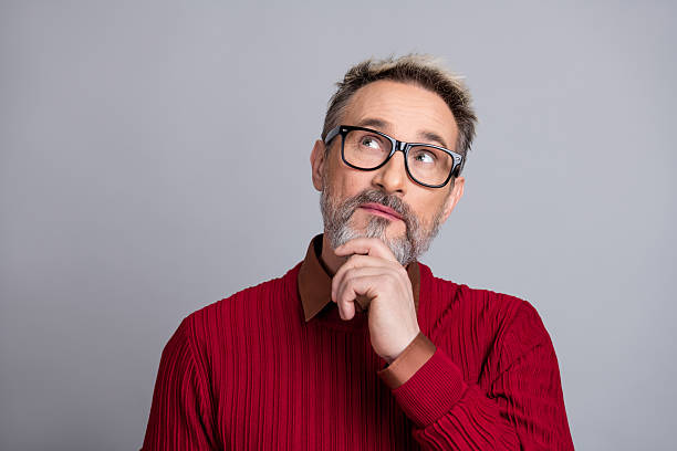 istock Businessman in casual red sweater contemplating ideas with thoughtful expression on light gray background 2240922972