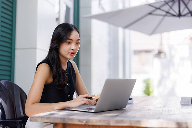 istock Young asian freelancer working on laptop in outdoor cafe 2240923019