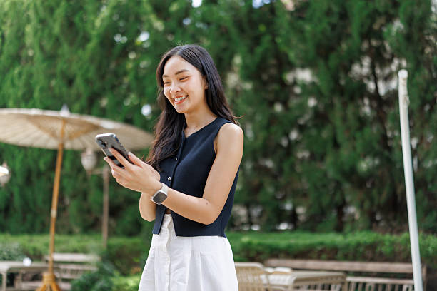istock Young asian woman using smartphone in a green park 2240923475