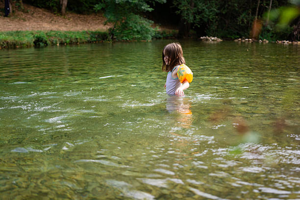 Cute little girl standing during summer day in the river