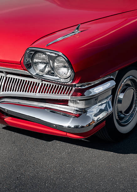 Classic american car on sunny day - close-up view of headlight, fender, bumper hood and wheel.