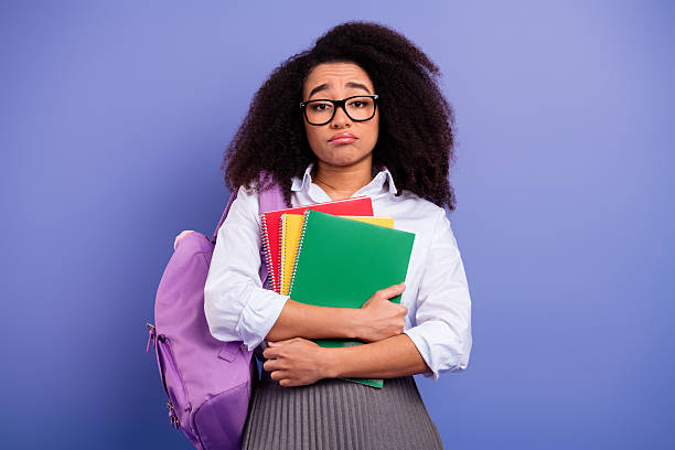 istock Young student with colorful notebooks and a backpack expressing a thoughtful mood on a purple background 2240925183