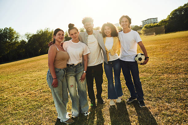 Large group of happy athletes having fun while taking a selfie with cell phone in the park.
