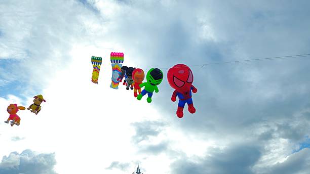 Can Tho, Vietnam - Feb 23, 2025: A group of colorful kites, shaped like cartoon characters and rectangular kite, is flying in the bright blue sky clouds.