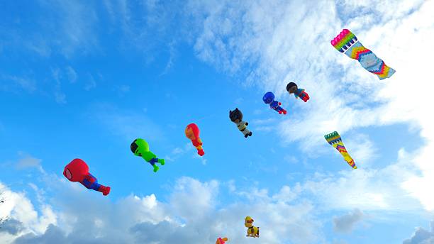 Can Tho, Vietnam - Feb 23, 2025: A group of colorful kites, shaped like cartoon characters and rectangular kite, is flying in the bright blue sky clouds.