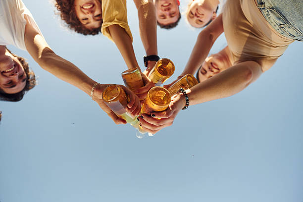 istock View from below of people that are cheering with beer bottles 2240927111