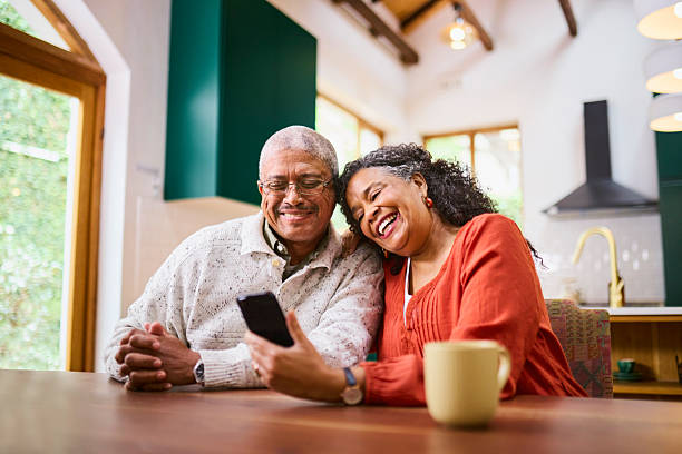 istock Joyful Senior Black Couple Laughing at Smartphone Over Coffee 2240927254