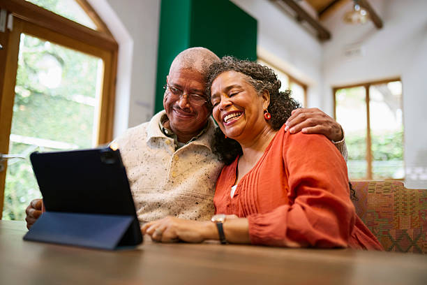 istock Joyful Senior Black Couple Embracing and Laughing at Digital Tablet 2240927288