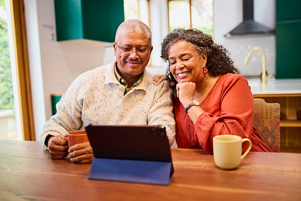 istock Happy Senior Black Couple Laughing at Tablet Over Coffee 2240927308