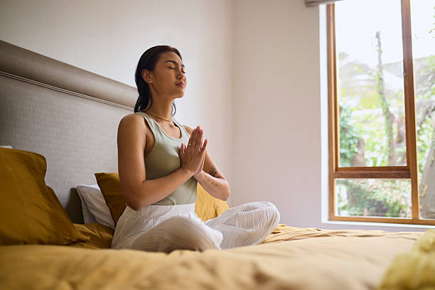 istock Peaceful Asian Woman Meditating in Prayer Pose on Bed 2240927756