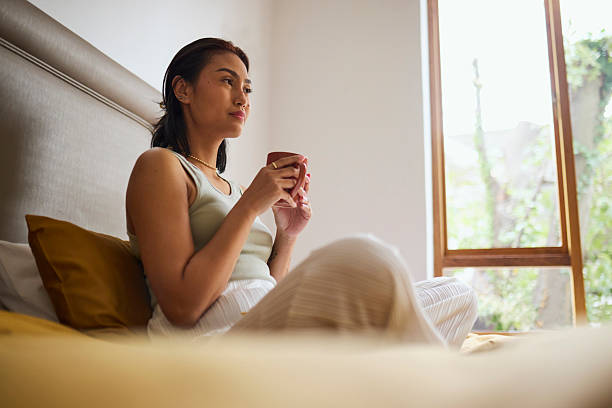 istock Asian Woman Contemplating While Sipping Coffee in Bed 2240927783