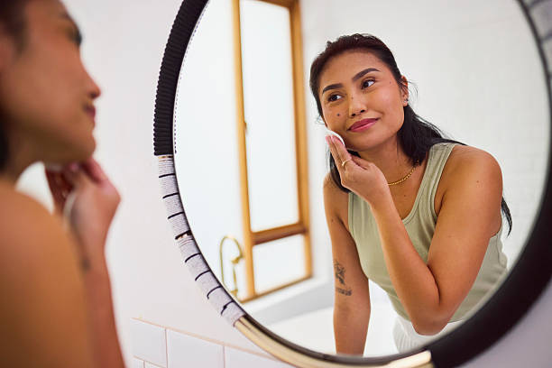 istock Asian Woman Applying Toner with Cotton Pad in Mirror Reflection 2240927840