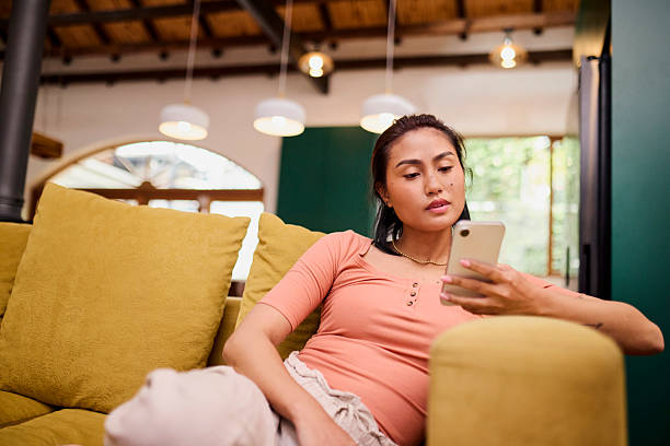 istock Serious Asian Woman on Couch Using Mobile Phone for Social Media or Browsing 2240927996