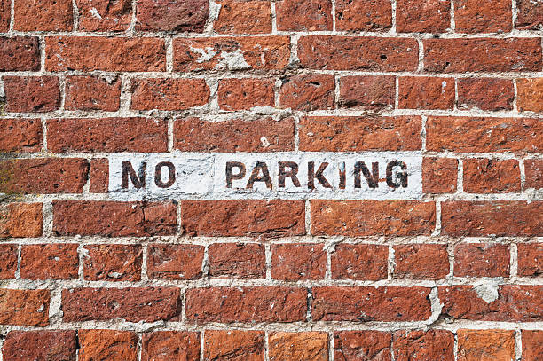 istock Hand painted No Parking sign seen on an old brick wall at a London design studio. 2240929126