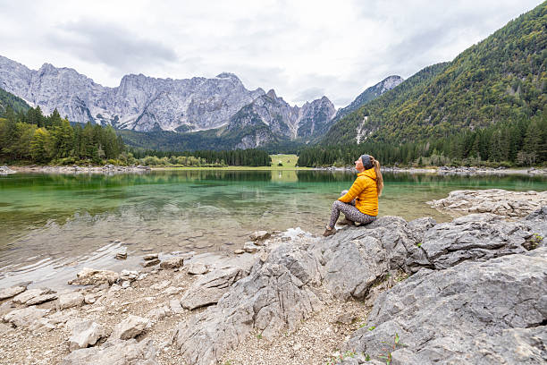 istock Woman Sitting on Rocks by Mountain Lake 2240931409