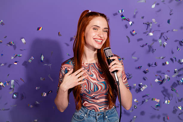 istock Smiling Young Woman Singing on Microphone with Confetti on Violet Background Promoting Lifestyle and Entertainment 2240931839
