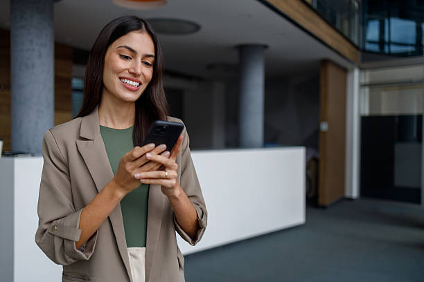 istock Businesswoman smiling, using phone, communicating and networking in modern office workspace 2240931891