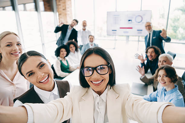 istock Group of cheerful professionals in an office setting taking a selfie, highlighting teamwork, collaboration 2240932082