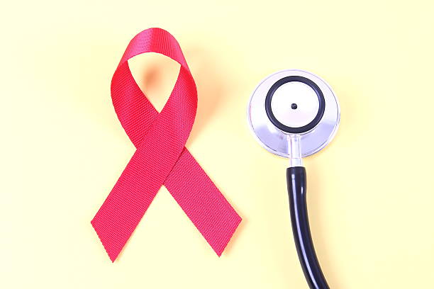 AIDS awareness red ribbon and stethoscope on yellow background