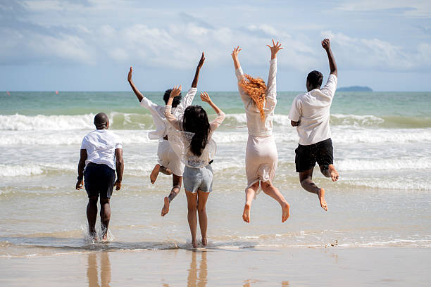 Group diversity people jumping in celebration on beach during summer vacation, happy friends enjoying freedom and fun together, friendship and excitement during travel holiday and relax.