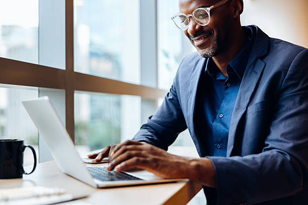 istock Businessman working on laptop at brightly lit office desk 2240940950