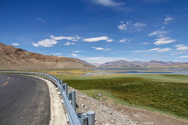 istock Scenic road with clear blue sky and vast grassland view 2240941593