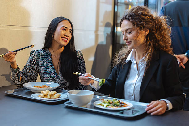 istock Two businesswomen sharing a lunch break in a modern self-service restaurant, smiling and chatting 2240942474