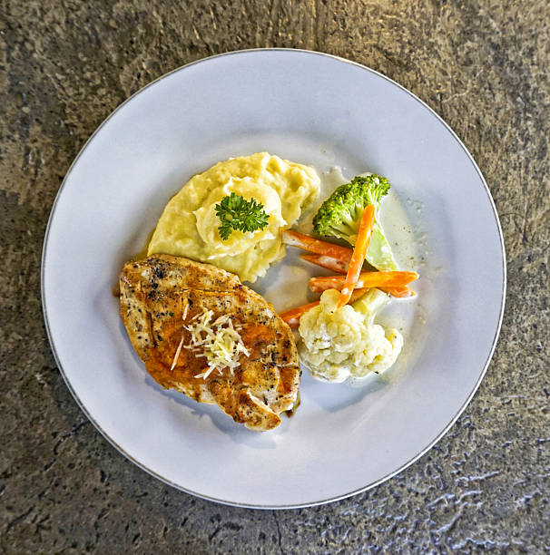 Rustic pan-seared chicken breast with creamy mashed potatoes and seasonal vegetables, overhead
