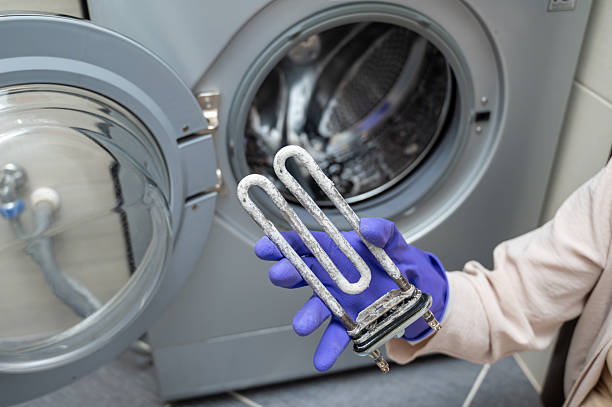 istock Person in gloves showing removed washing machine heating element covered with limescale 2240947233