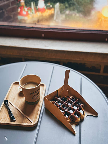 Close up of coffee and  a Belgian waffle drizzled in chocolate sauce, cozy breakfast or snack in Belgium.