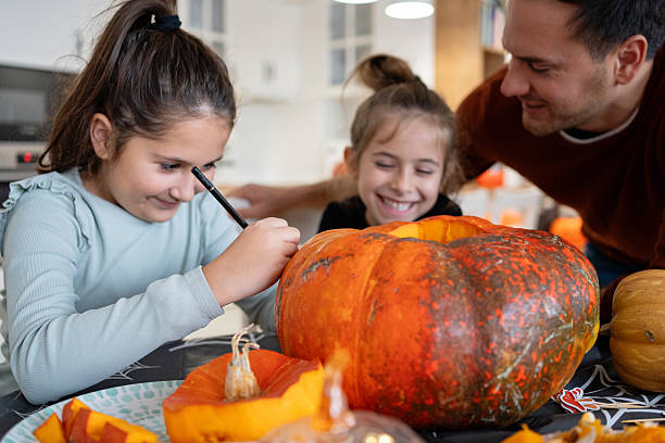istock Dad and daughters creating a Halloween pumpkin together at home 2240951419