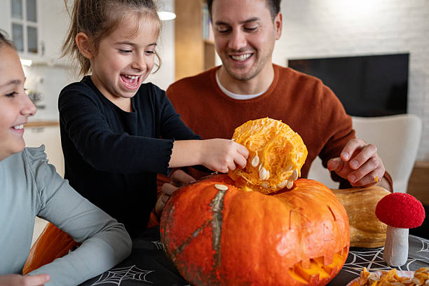 Dad and two daughters decorating a Halloween jack-o’-lantern