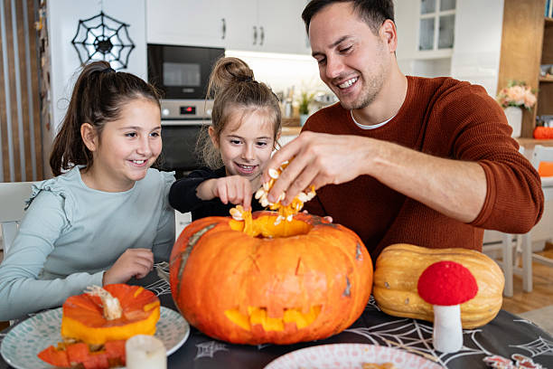 istock Father and two daughters scooping seeds from a Halloween jack-o’-lantern 2240951707