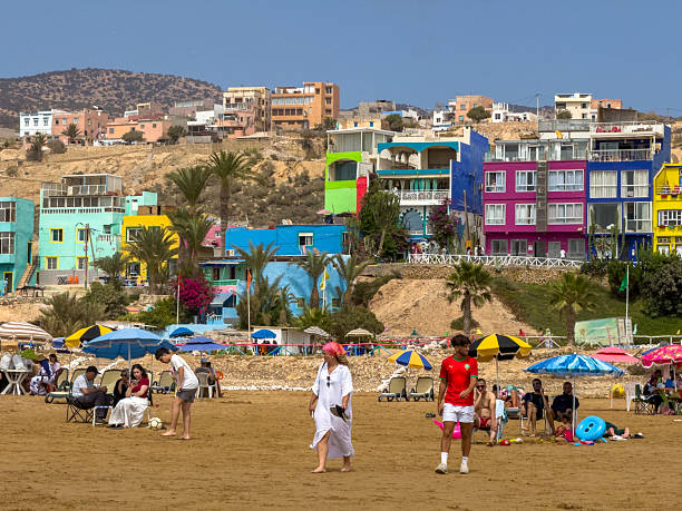People chilling on the beach next to colourful houses in Aghroud