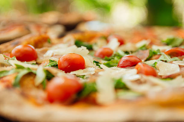 Delectable pizza resting outdoors with cherry tomatoes, arugula, and parmesan flakes