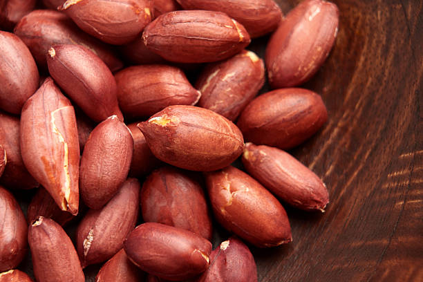 istock Shelled roasted peanuts in red skin on wooden texture 2240956231