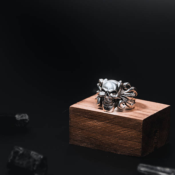 Studio photo of a silver skull ring with dark  background upon a greek column with perfect lightning