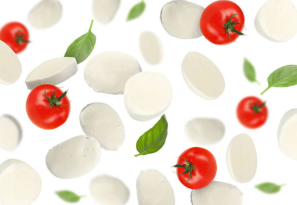 istock Mozzarella, tomatoes and basil leaves falling against white background 2240958576