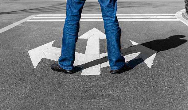 istock Man standing on road with three direction arrow and get to decision which way to go 2240966004