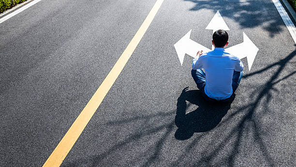 Man sitting on road with three direction arrow and get to decision which way to go