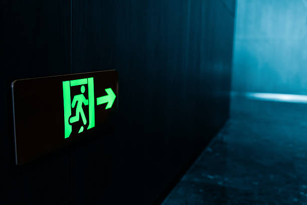 Green fire exit sign is placed on the wall of hotel corridor