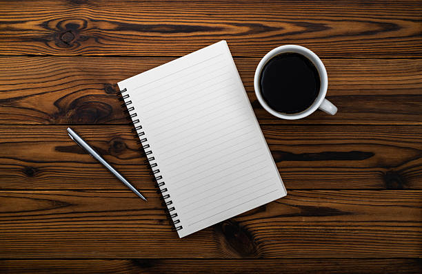 A cup of hot black coffee to start the week off right joined by a note pad and pink pen on this marble counter top.