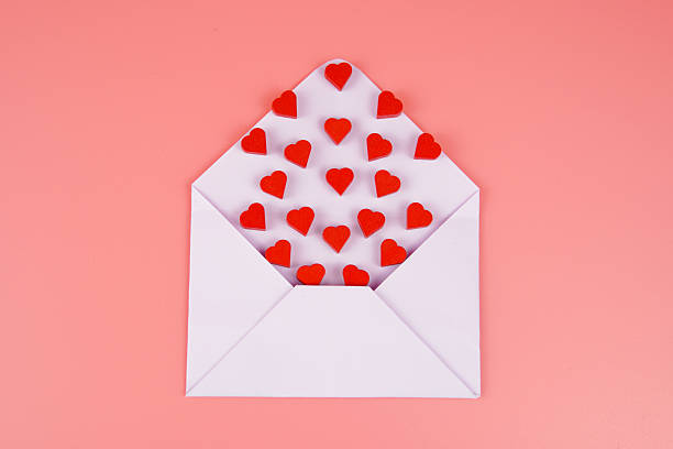 istock Flat lay of a white envelope filled with small red hearts on a pink background, symbolizing love, affection, romance, and emotional connection. Perfect for Valentine's Day, weddings, or romantic messages. 2240977092