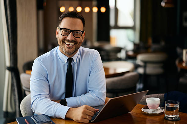 istock Happy businessman working on laptop in a cafe and looking at camera. 2240981295