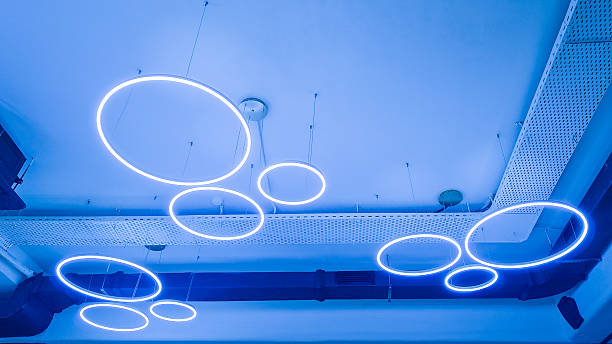 istock Circular luminaires on white ceiling. Circular LED luminaires on suspended ceiling, modern lighting system for office space, co-working spaces, conference rooms, educational institutions. Real photo 2240981557