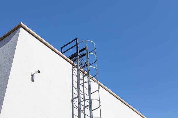 istock Metal fire escape ladder on building corner against clear blue sky. Safety structure for emergency access in modern architecture. Real photo 2240981567
