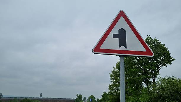 istock Triangular traffic sign warning of upcoming intersection on country road 2240981572