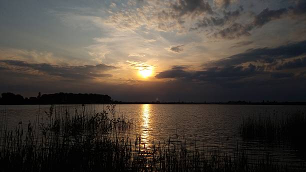 Serene sunset view over tranquil lake water with dark clouds