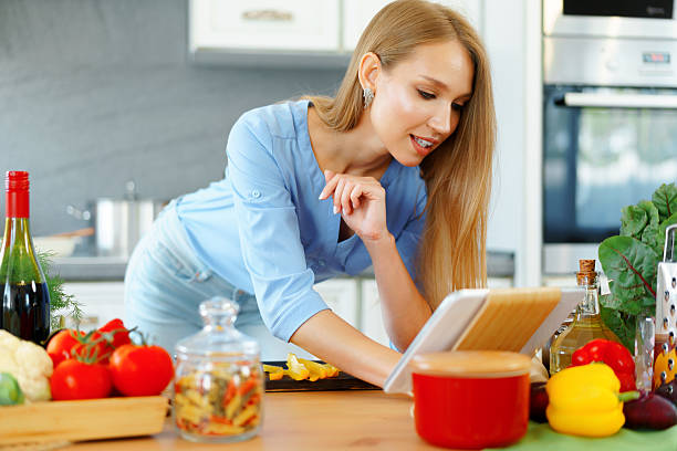 istock Young beautiful caucasian woman cooking and using her digital tablet in kitchen 2240982009
