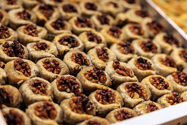 Close-up of round Turkish baklava sweets filled with walnuts, arranged in rows in a metal tray, showing golden crust and nut texture.